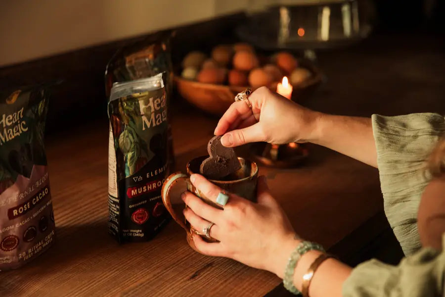 Fingers lowering an embossed cacao heart into a ceramic mug