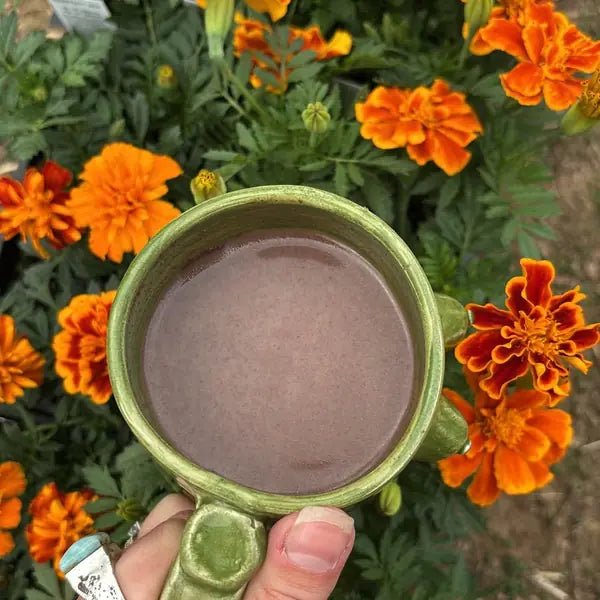 A green mug of cacao among orange marigolds, from Jeannie J.'s review