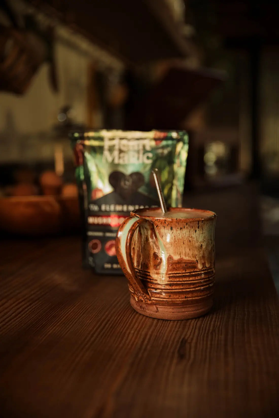 A frothy mug of cacao in front of a bag of Heart Magic Elemental