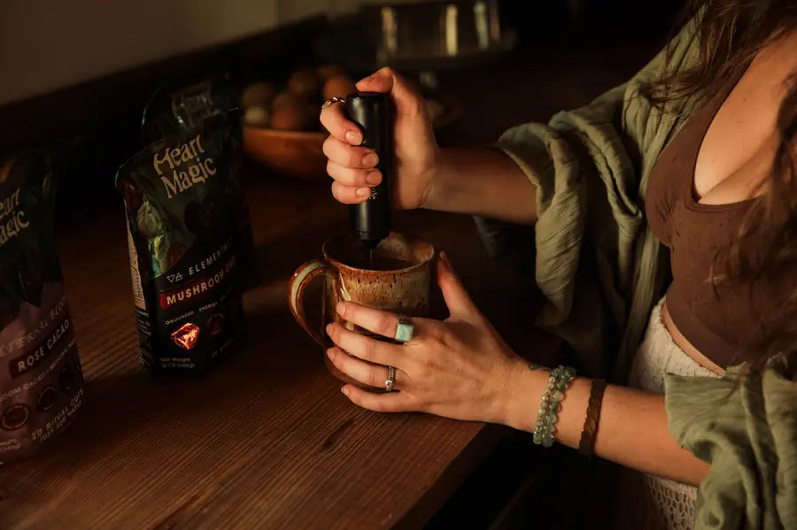 A handheld frother whisking cacao in a speckled mug