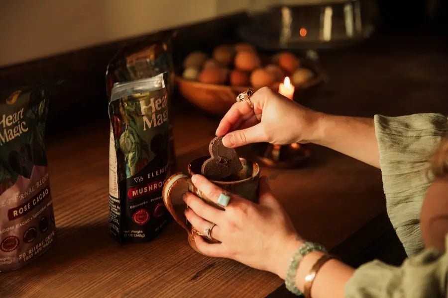 Fingers lowering an embossed cacao heart into a ceramic mug