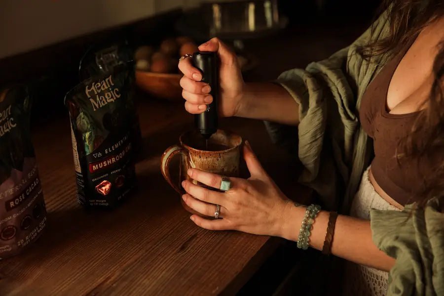 Frothing a mug of cacao, the Elemental bag on the counter behind it