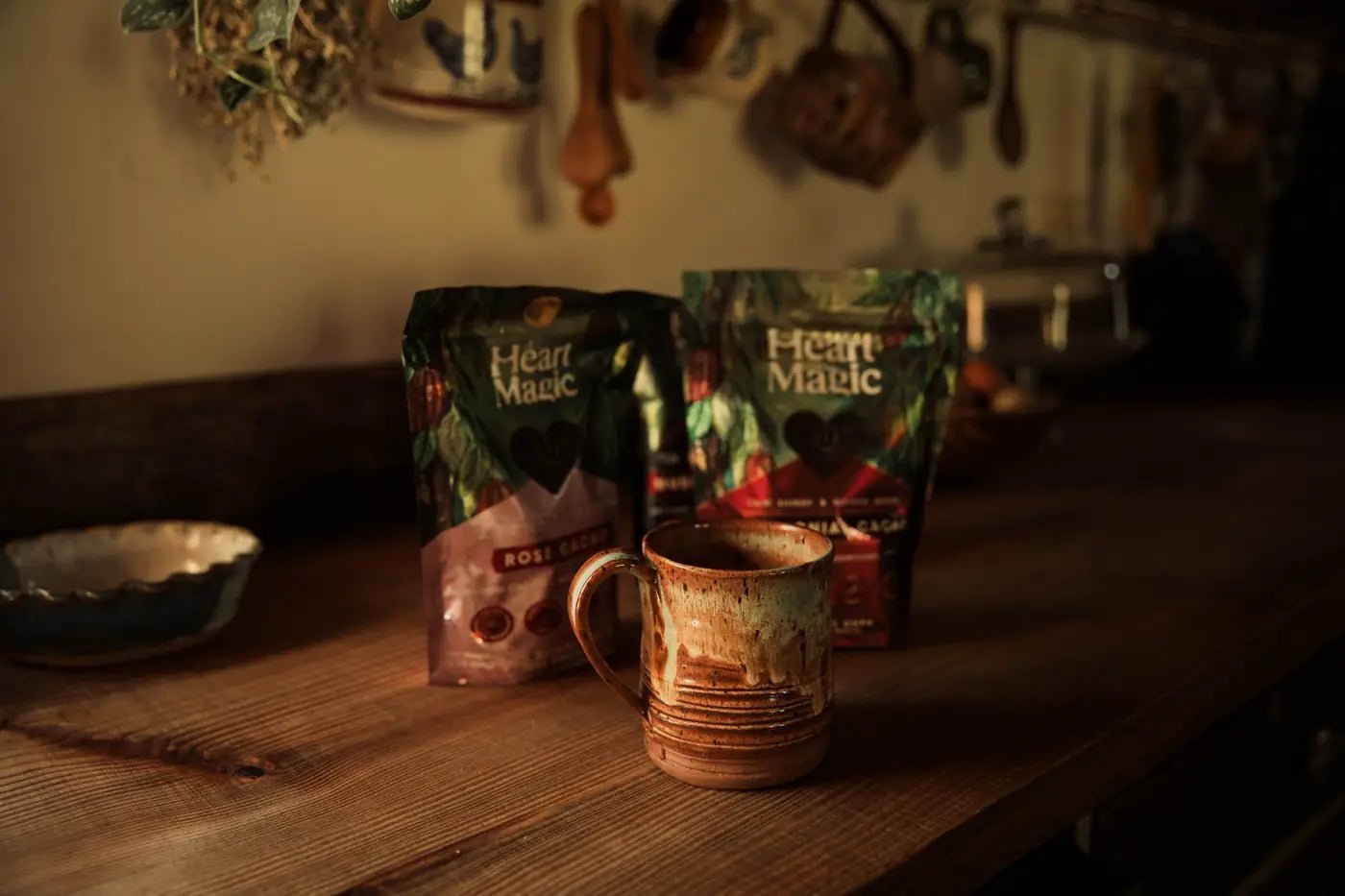 Two bags of Heart Magic cacao hearts beside a warm mug of cacao