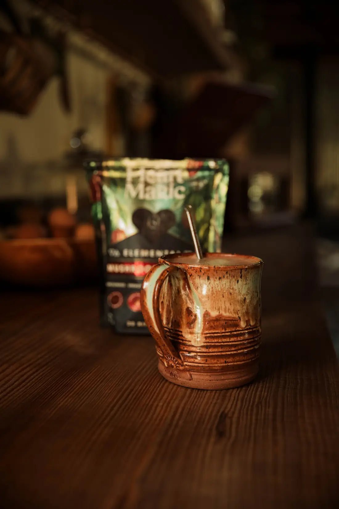 A bag of Heart Magic Elemental cacao hearts beside a frothed mug on a wooden counter